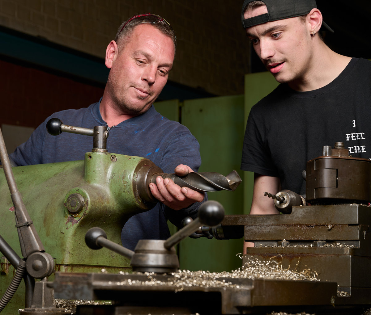 weiss-edelstahlbearbeitung-drehmaschine Zwei Mitarbeiter an einer Drehmaschine mit eingespanntem Werkstück